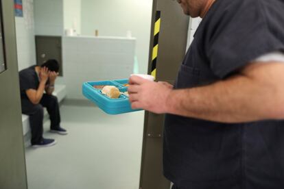 Un inmigrante lleva la comida al interior de su celda en el centro de Adelanto.