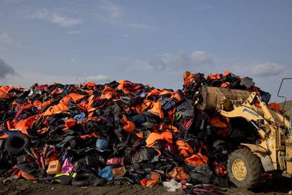 Una excavadora apila chalecos salvavidas y botes que han sido utilizados por los migrantes en un vertedero local de la isla de Lesbos, Grecia.