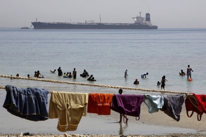 Un barco navega por el Golfo de Suez hacia el Mar Rojo mientras bañistas egipcios juegan en la playa de Sokhna, al este de El Cairo, Egipto.