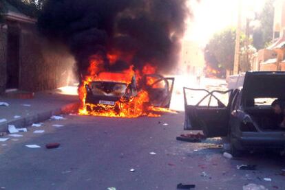 Un coche arde mientras otro es desmantelado en una calle de El Aaiún.