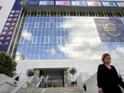 Una mujer chipriota camina delante de un enorme s&iacute;mbolo del euro en la fachada del Banco Central en Nicosia, Chipre. 