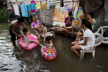 Una familia sentada fuera de su casa, cerca del río Chao Praya river en Bangkok