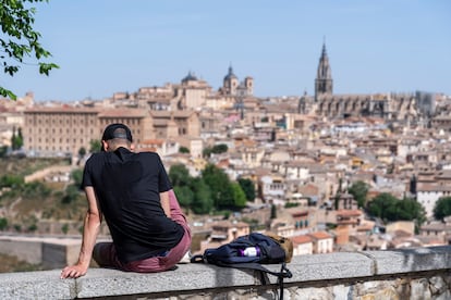 Un chico descansaba el jueves bajo el sol con la ciudad de Toledo de fondo.