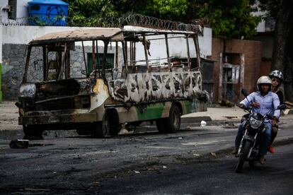 Un autob&uacute;s incendiado durante los disturbios de este domingo.