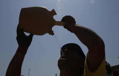 Un obrero se refresca con agua bajo un intenso sol en un edificio en construcción en Pamplona.