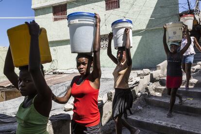 Las jóvenes trasladan hasta sus casas los bidones de 19 litros de agua potable.