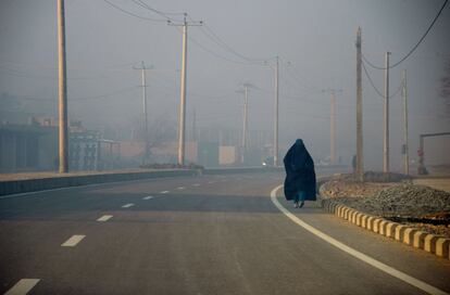 Una mujer afgana con burka camina a lo largo de una carretera en Mazar i Sharif (Afganistán).