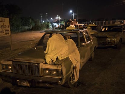 Un hombre duerme sobre su auto mientras espera por gasolina en Maracaibo.