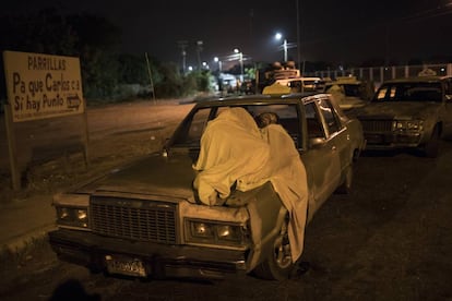 Un hombre duerme sobre su auto mientras espera por gasolina en Maracaibo.