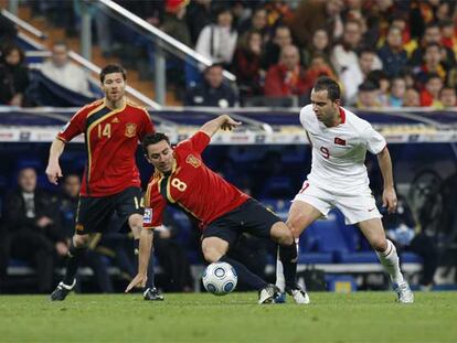 Xavi pelea un balón con Senturk, con Xabi Alonso siguiendo la jugada.