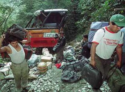 Varios empleados recogen el equipaje de un autobús accidentado en Yolosa, en la región de Yungas