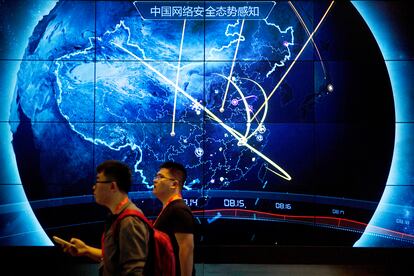 Attendees walk past an electronic display showing recent cyberattacks in China at the China Internet Security Conference in Beijing