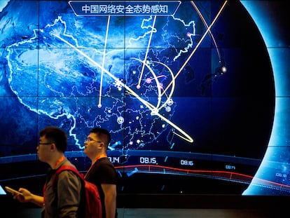 Attendees walk past an electronic display showing recent cyberattacks in China at the China Internet Security Conference in Beijing