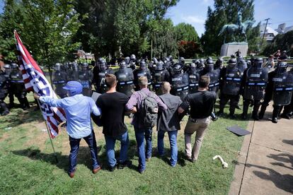 A policial interpõe-se entre um grupo de supremacistas e a estátua do general Robert E. Lee.