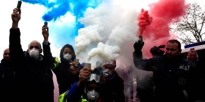 Conductores de ambulancia franceses sostienen bombas de humo azules, blancas y rojas, formando los colores de la bandera francesa, durante una manifestación en la Plaza de la Concordia, en París.