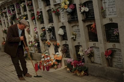 Un hombre limpia el suelo junto a unos nichos en el cementerio de Pamplona (España).