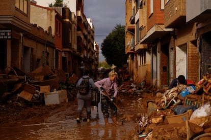 Una vecina de Sedaví limpian el lodo de una calle, este lunes. 