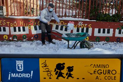 Un familiar colabora en la limpieza del hielo y la nieve en las inmediaciones del colegio Amadeo Vives tras la nevada.