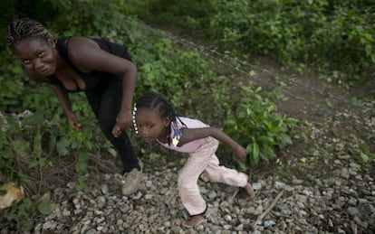 Uma imigrante hondurenha e sua filha tentam alcançar o trem em Chiapas, México.