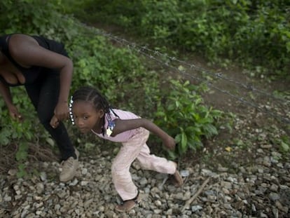 Uma imigrante hondurenha e sua filha tentam alcançar o trem em Chiapas, México.