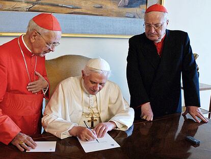 El Papa firma un documento en presencia de los cardenales Angelo Sodano (derecha) y Eduardo Martínez Somalo.