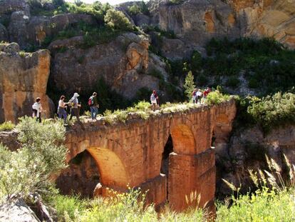 Excursionistas cruzando el acueducto de la Peña Cortada, de donde cayó la mujer fallecida, en una imagen de la web del Ayuntamiento de Calles.