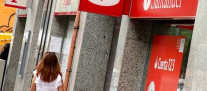 Una mujer camina delante de una oficina de Banco Santander y Banco Popular