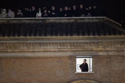 Una mujer espera junto a una ventana el anuncio del nombre del nuevo papa en uno de los balcones de la plaza de San Pedro en el Vaticano.