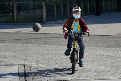 Menino anda de bicicleta com uma máscara em Pequim.