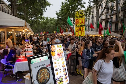 Una manifestación contra el turismo de masas pasa frente a restaurantes turísticos en las Ramblas de Barcelona.