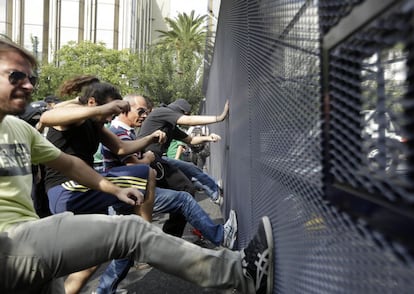 Manifestantes tratan de derribar la barrera que protege el Parlamento en Atenas.