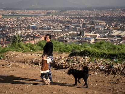 Una mujer camina con su nieta en un barrio con alto índice de pobreza en Colombia.