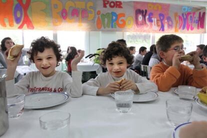 Alumnos del colegio Os Dices comen bocadillos en el comedor escolar.