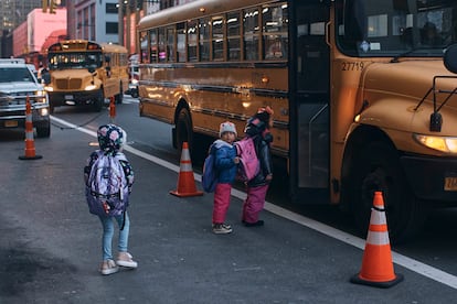 Migrant children board a bus that takes them to school, in front of the Row Hotel, on December 12, 2023.