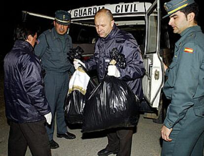 Agentes de la Guardia Civil y de la policía transportan en bolsas los restos humanos.