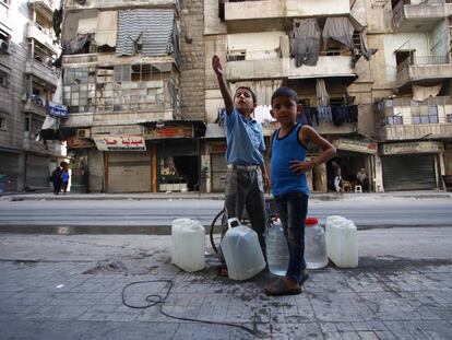 El pasado seis deoctubre, Abdulghani, de nueve años (izquierda) y su hermano Hassan, de seis, esperan su turno para rellenar sus bidones con agua de un pozo en la calle en la parte este de Alepo (Siria).
