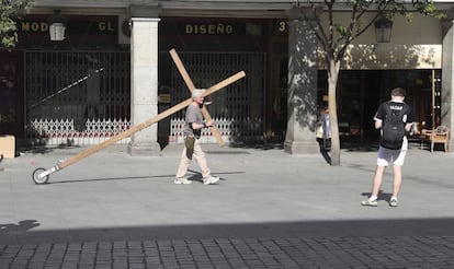 Un hombre transporta una cruz por la Plaza de La Provincia en el primer día festivo de la Semana Santa en Madrid.