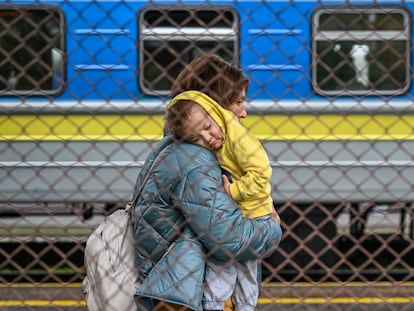 A Ukrainian woman carries her child as they get off a train from Zaporizhzhia at Przemysl train station on September 30, 2022 in Przemysl, Poland.