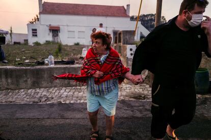 Una mujer es evacuada de su casa durante el incendio forestal en la localidad portuguesa de Cascais, este martes.