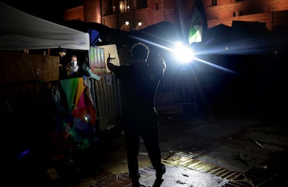 Un joven hace señas obscenas a personas refugiadas tras la barricada del campamento de manifestantes propalestinos en la Universidad de California en Los Ángeles.
