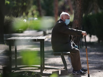 Un anciano con mascarilla descansa en el Parque Calero, en Madrid.