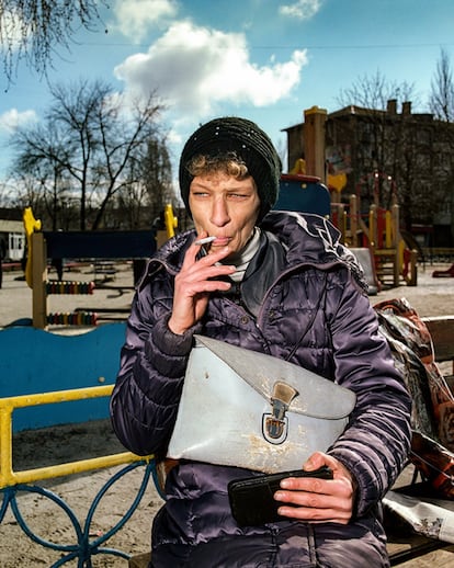 Mujer fumando en un banco en Myrnohrad, Donetsk, 2021.