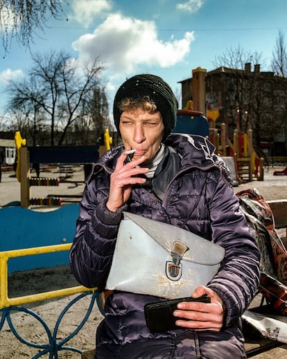 Mujer fumando en un banco en Myrnohrad, Donetsk, 2021. 