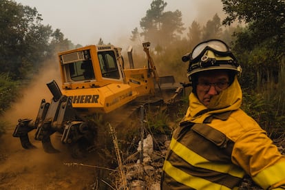 Bomberos construyen un cortafuegos para evitar que un incendio forestal alcance la iglesia de Santa María de Retorta en la ciudad de Ourense, el domingo.