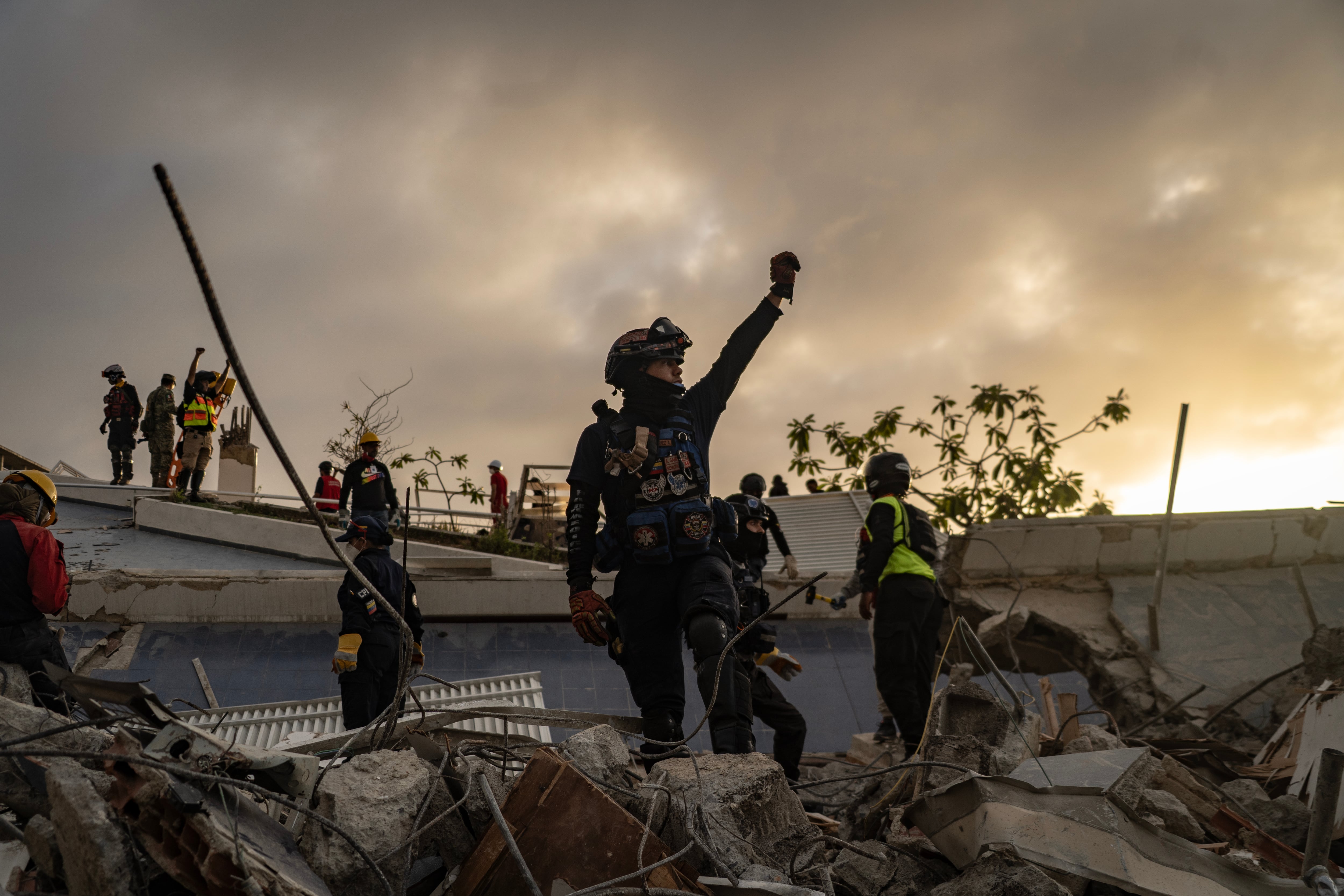 Los rescatistas levantan la mano para poder escuchar a los sobrevivientes del colapso de un edificio en La Guaira.