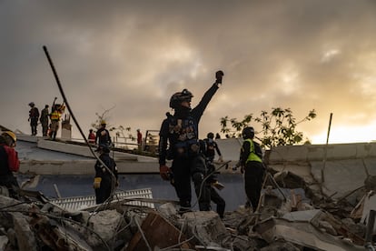 Los rescatistas levantan la mano para poder escuchar a los sobrevivientes del colapso de un edificio en La Guaira.