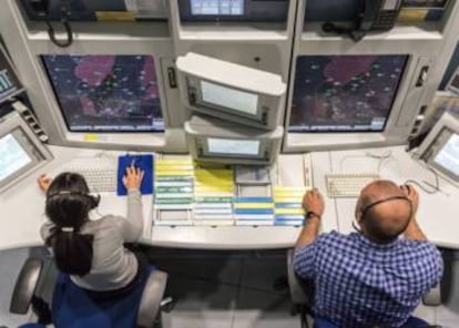 Dos controladores vigilan los vuelos de aviones.