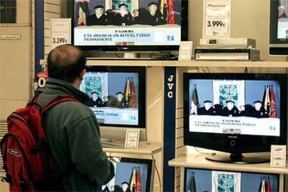 Un ciudadano observa en un escaparate de Bilbao el vídeo en el que ETA anuncia el alto el fuego permanente.
