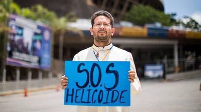 Um sacerdote sustenta um cartaz em frente à sede do Serviço de Inteligência, em Caracas.