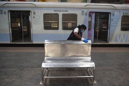 A railway worker cleans a bench on a platform after the government eased a nationwide lockdown imposed as a preventive measure against the COVID-19 coronavirus, at the Churchgate railway station in Mumbai on June 15, 2020. (Photo by Punit PARANJPE / AFP)